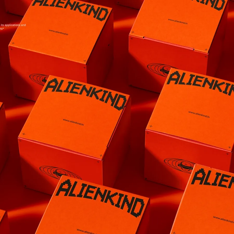 ALIENKIND branded orange shipping boxes with pixel wordmark by StudioDraft